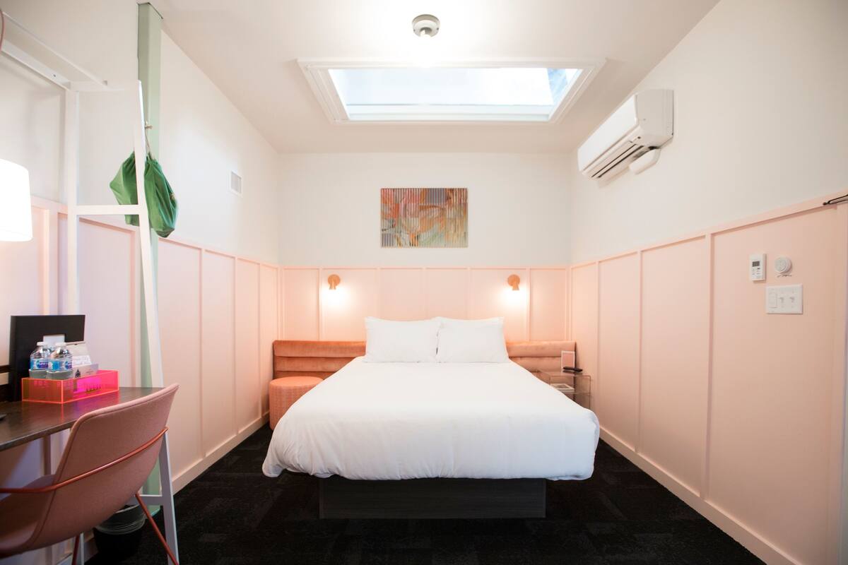 Ein Hotelzimmer mit Bett, Schreibtisch, Stuhl und einem Oberlicht.