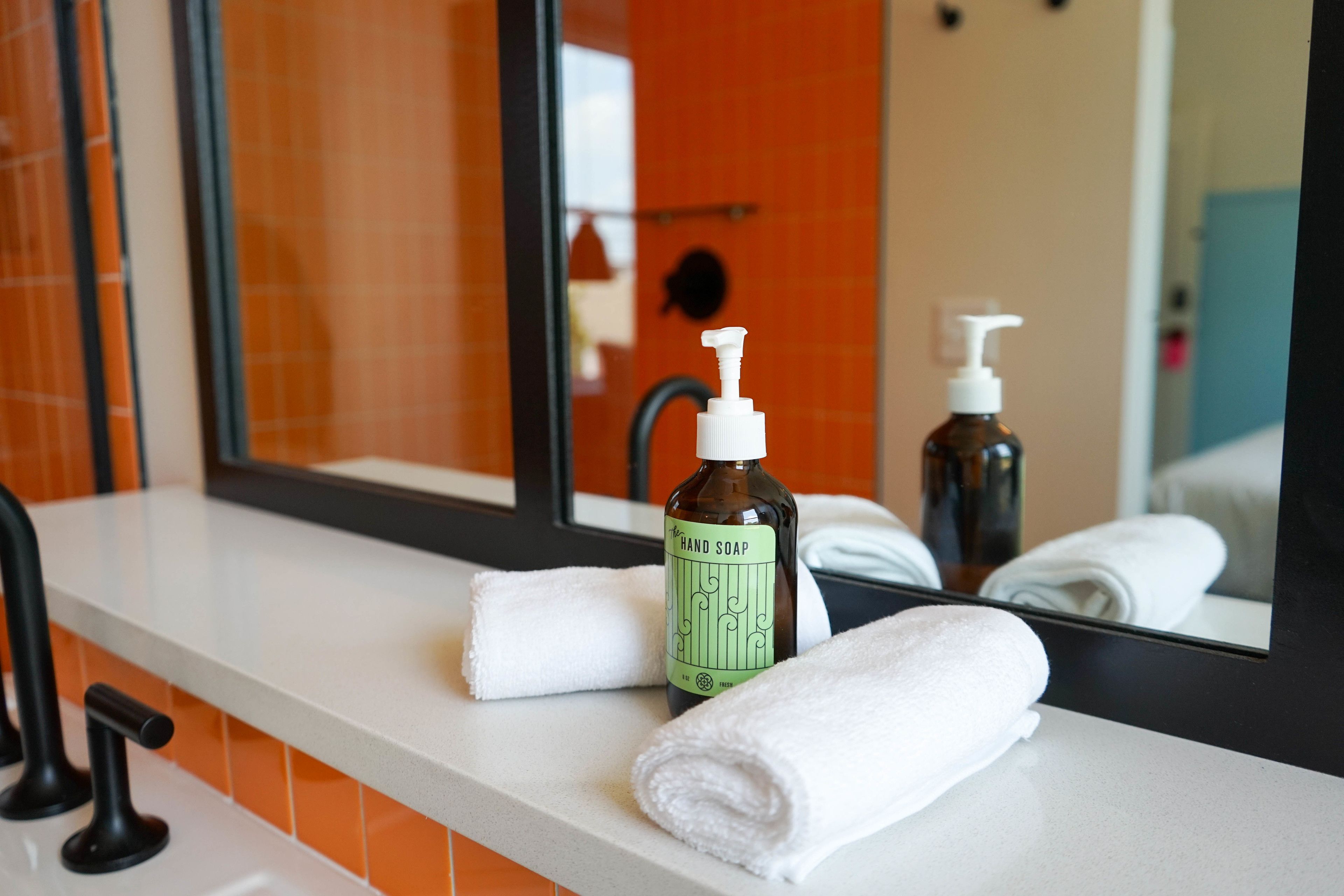 A bathroom with a white countertop, a hand soap dispenser, and a towel.