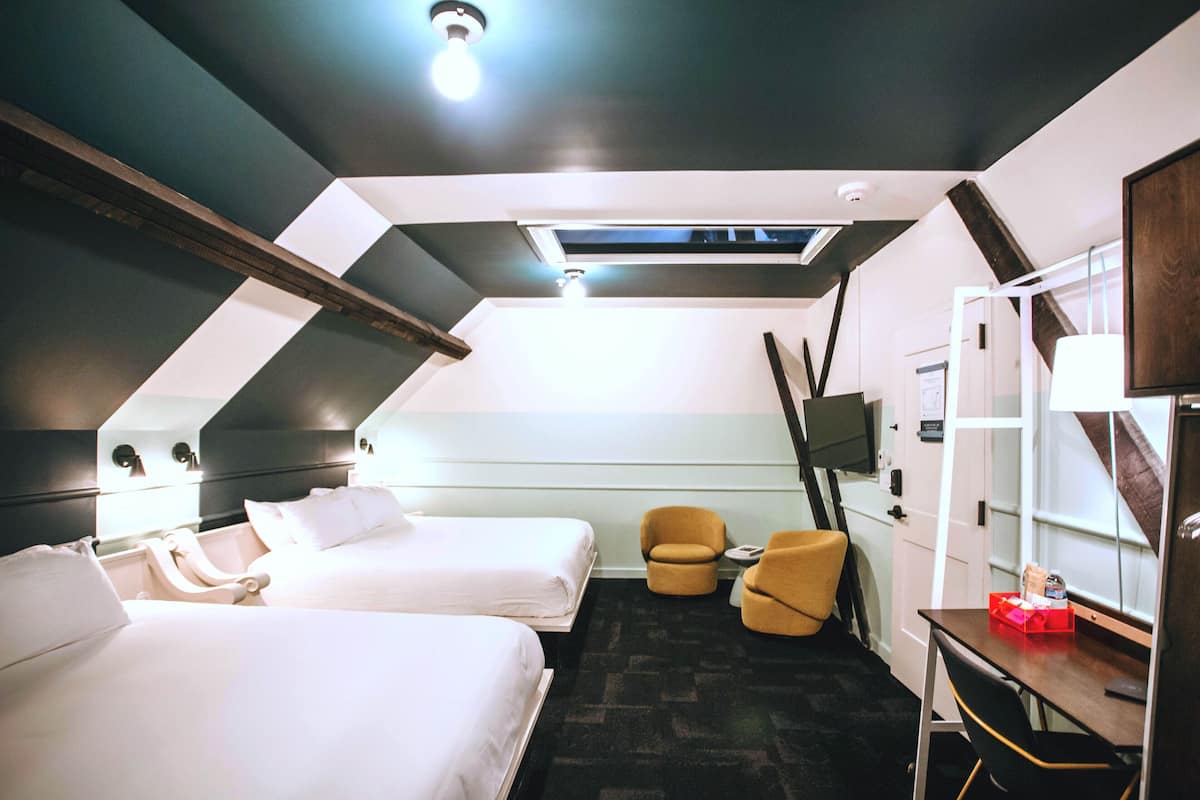 Ein Hotelzimmer mit zwei Betten, einem Schreibtisch, einem Stuhl und einem Fernseher.
