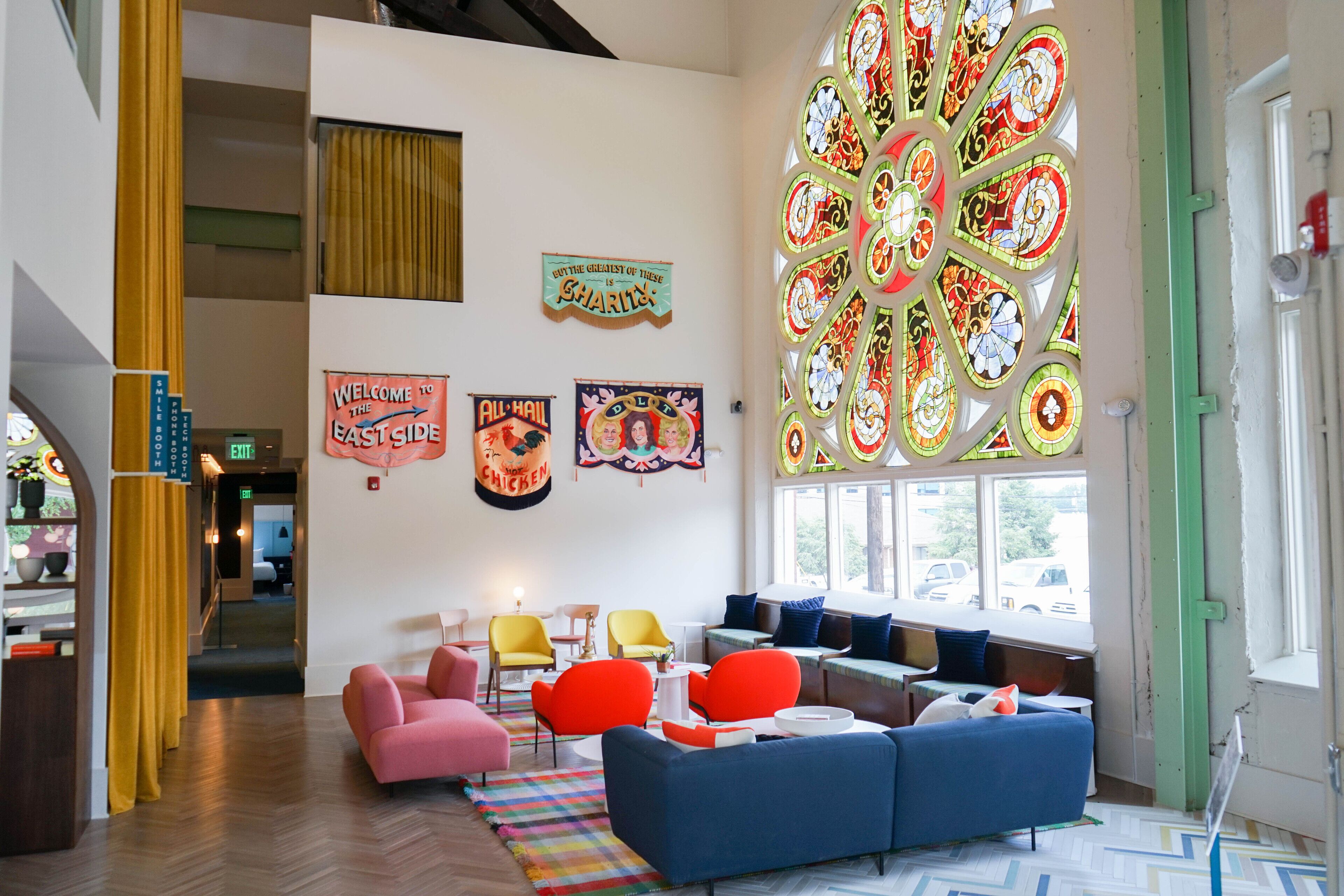 A modern interior with a large stained glass window, colorful wall art, and a variety of seating options.