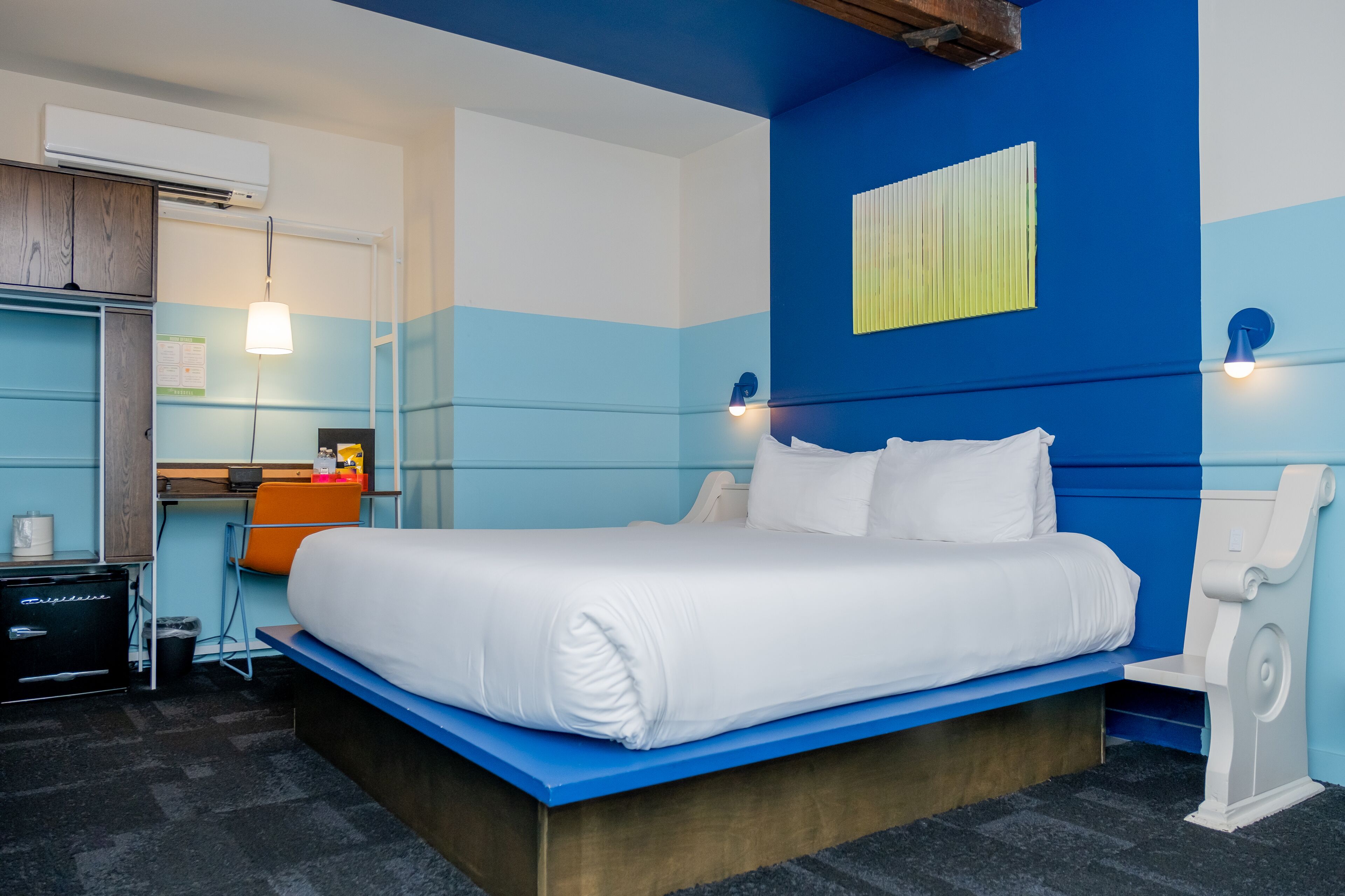 A modern hotel room with a large bed, a desk, and a chair.