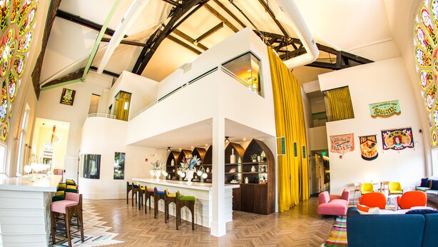 Un loft espacioso con techo alto, un nivel entre piso y una zona de cocina.