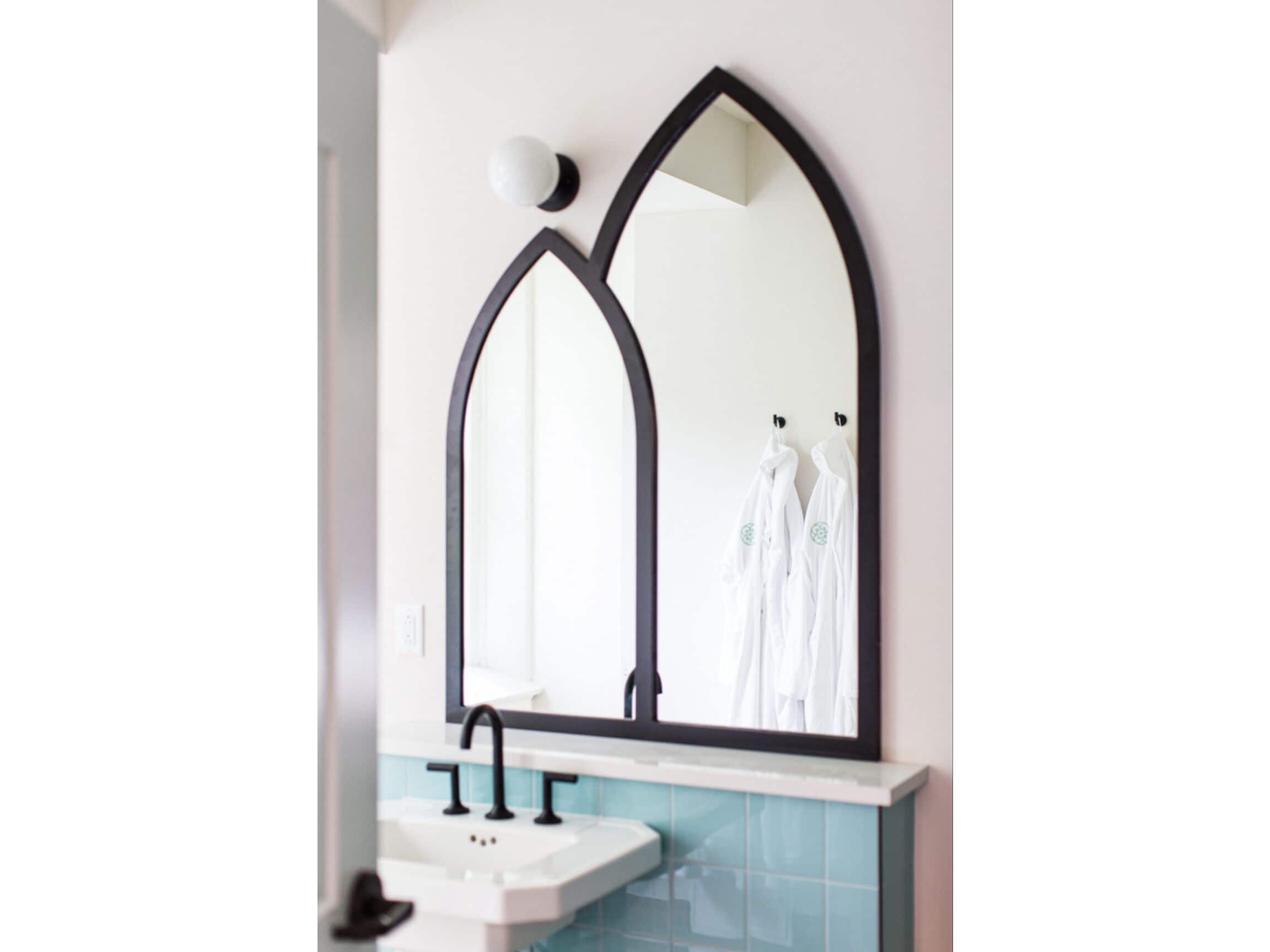 A bathroom with a white sink, a mirror with a black frame, and a towel rack with white towels.