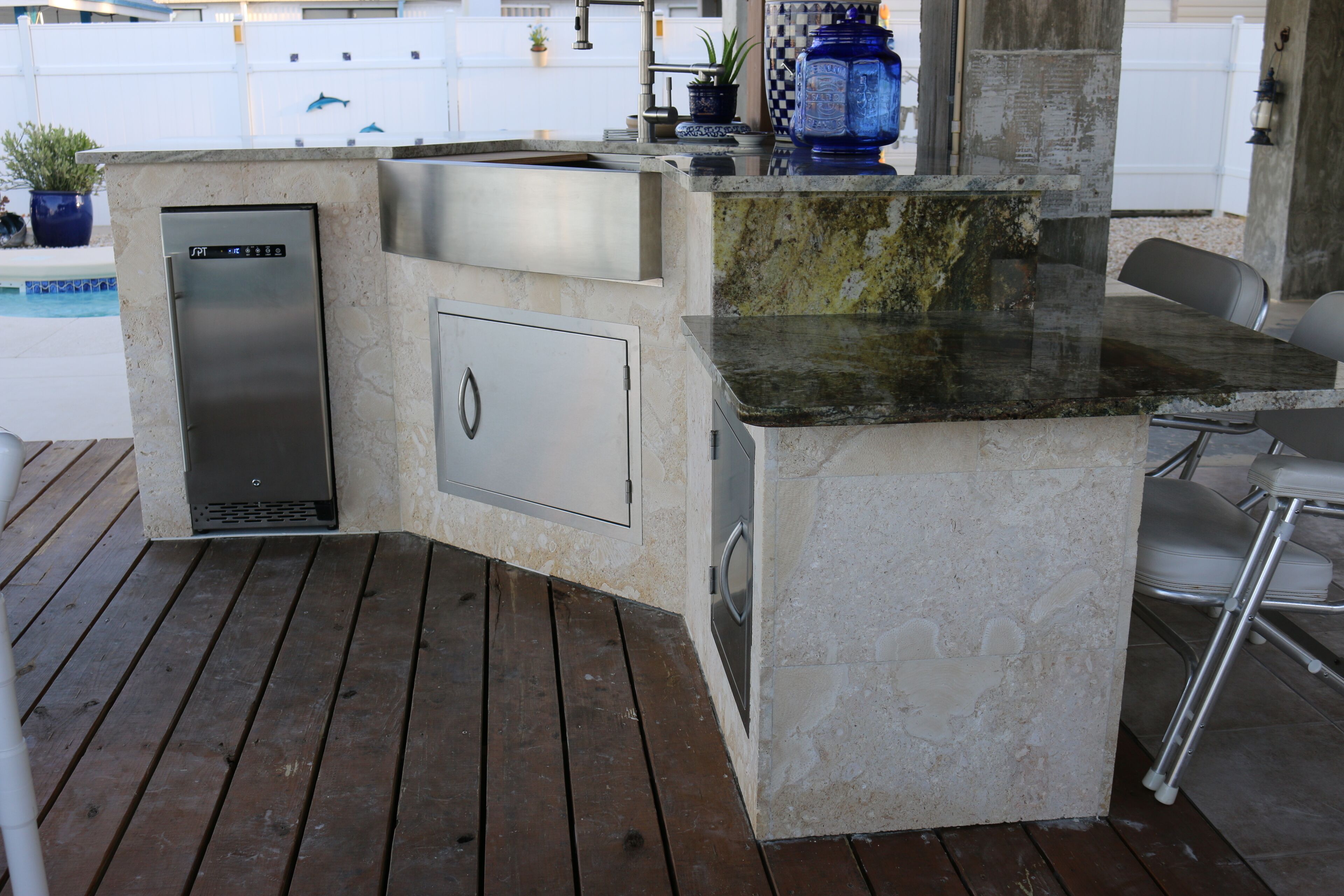 A kitchen island with a built-in sink, a stainless steel refrigerator, and a marble countertop.