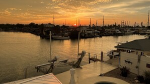 A marina at sunset with boats docked, a swimming pool, and a dock extending into the water. - Copacabana, Overlooking the Gulf! (Marathon)