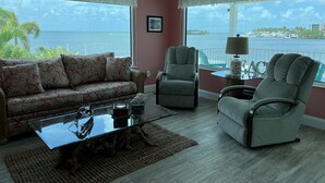 A living room with a sofa, two armchairs, a glass coffee table, and a view of the sea. - Copacabana, Overlooking the Gulf! (Marathon)
