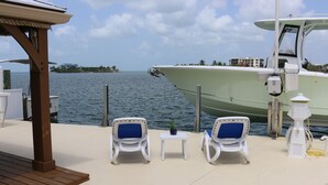 A boat docked at a marina with lounge chairs and a small table. - Copacabana, Overlooking the Gulf! (Marathon)