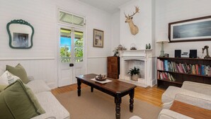 A living room with a fireplace, bookshelves, a mounted deer head, and a door with a view of greenery.