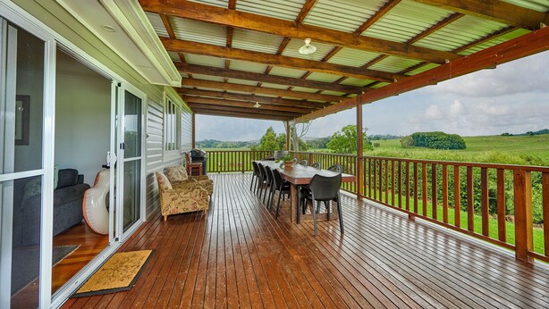 A covered outdoor deck with a dining table and chairs, a sofa, and a grill.