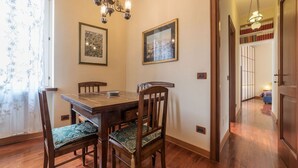 Un comedor con mesa y sillas de madera, obras de arte en las paredes y una lámpara de araña.