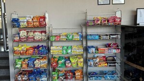 Three metal shelves stocked with various snack bags.