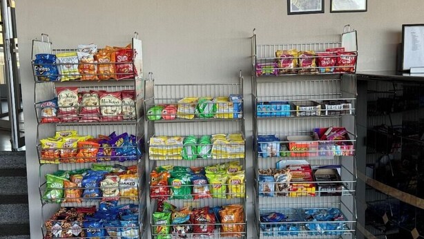 Trois étagères en métal remplies de différents paquets de collations.