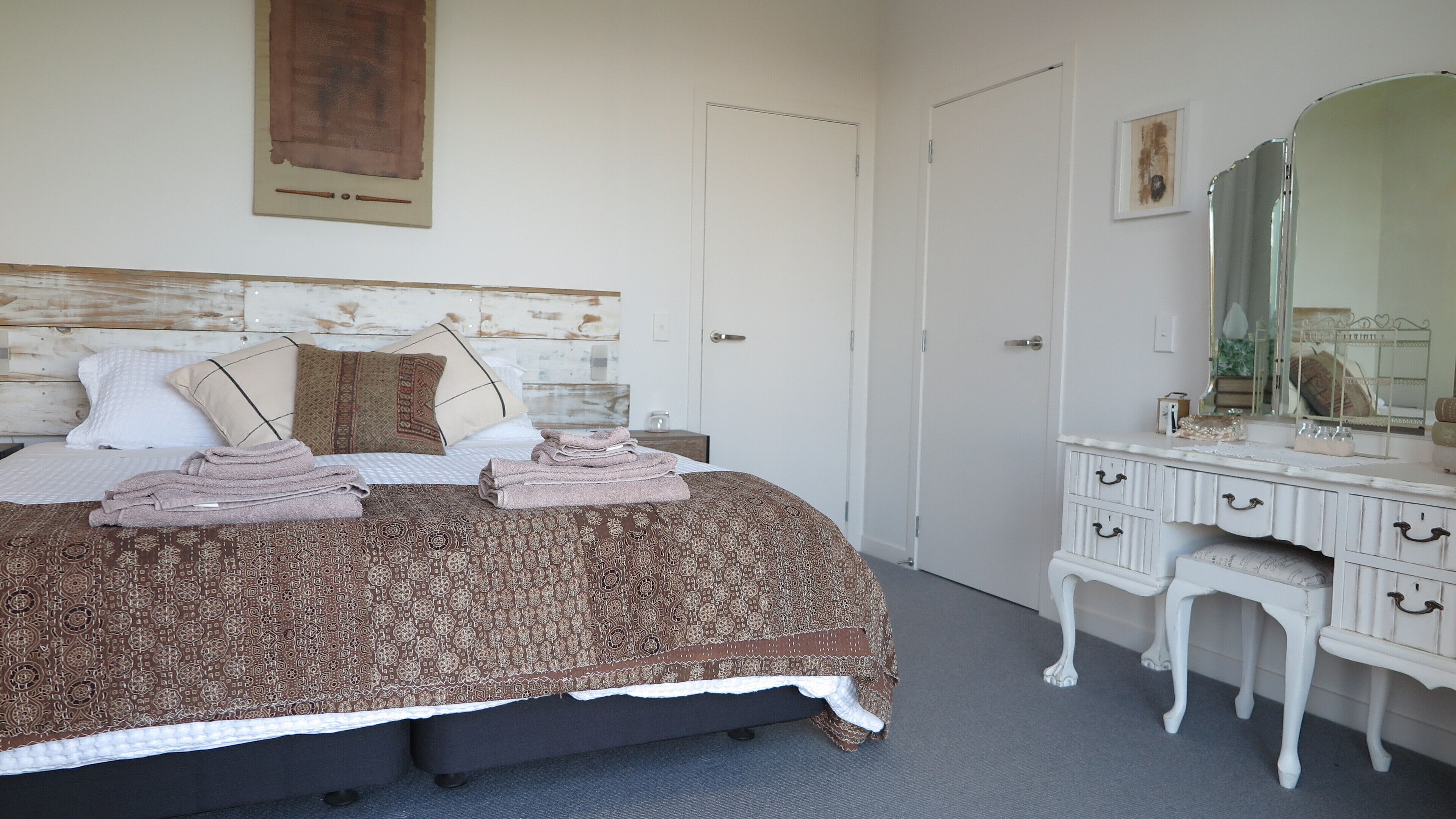 A bedroom with a bed, a dresser, a mirror, and a door.