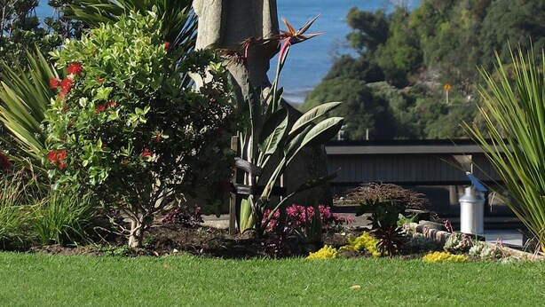 Une sculpture en pierre dans un jardin offrant une vue sur la mer et les collines lointaines.
