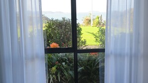 Une pièce dotée d’une grande porte-fenêtre coulissante donnant sur un balcon avec vue sur un jardin et un paysage lointain.