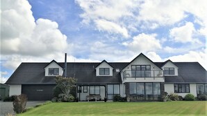 Une maison à deux étages, avec un toit sombre, de grandes fenêtres et une pelouse bien entretenue.