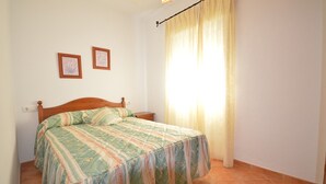 Une chambre à coucher avec un lit, une table de chevet et deux tableaux encadrés accrochés au mur.