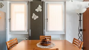 Ein Essbereich mit einem Holztisch, zwei Stühlen, einer dekorativen Tischmitte und Wandbildern mit Schmetterlingen.