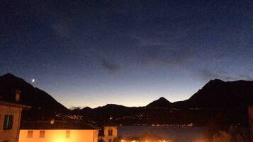 A nighttime view of a coastal town with buildings and a mountain in the background.