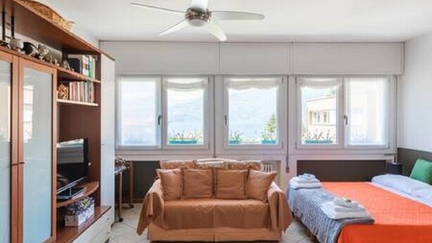 Ein Zimmer mit einer Couch, einem Bett, einem Deckenventilator und einem Fenster mit Blick.