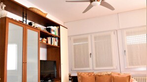 Ein Wohnzimmer mit Holzschrank, Fernseher und Deckenventilator.