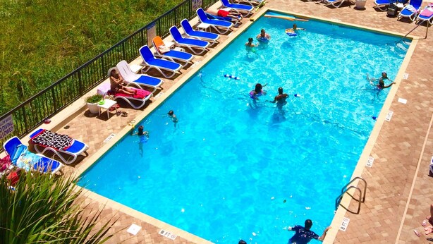Un área de piscina con varias piscinas, tumbonas y sombrillas.