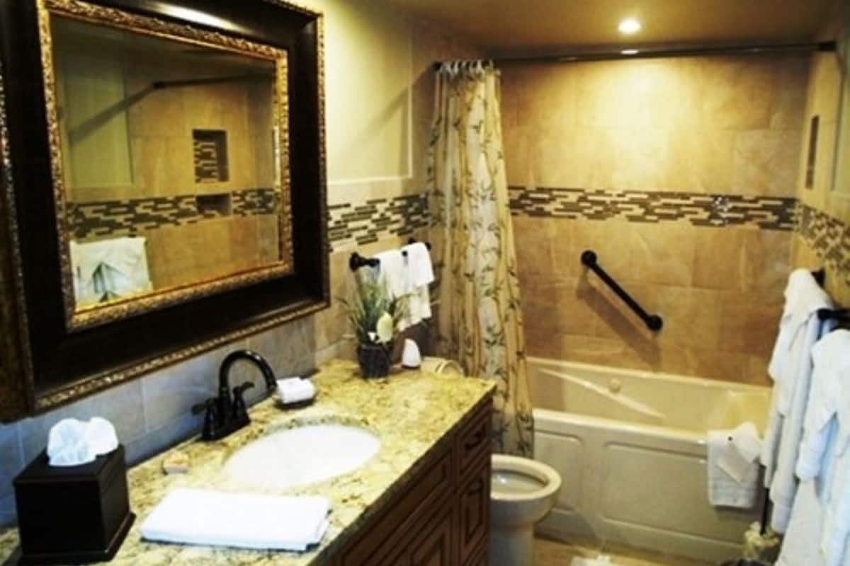 Un baño con lavamanos, espejo, tocador, inodoro y bañera.