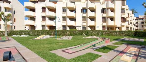 A residential building with multiple balconies, a well-maintained lawn, and a clear sky.