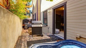 Un jardin avec un jacuzzi, un barbecue et une terrasse en bois.