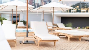 A rooftop pool area with wooden lounge chairs and white umbrellas. - Schgaguler Hotel (Castelrotto)
