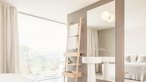 A modern bathroom with a large mirror, a white sink, and a wooden towel rack. - Schgaguler Hotel (Castelrotto)