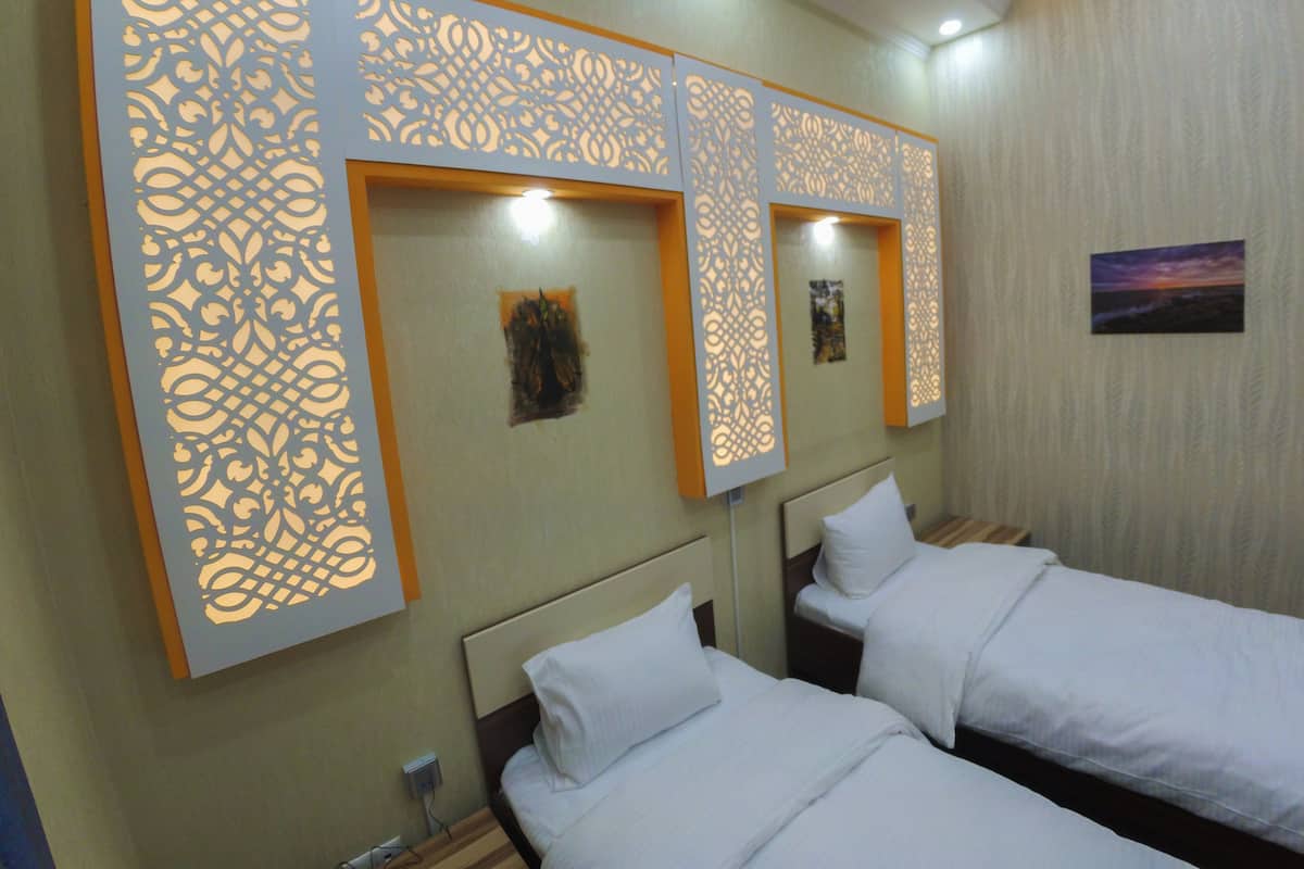A hotel room with two beds, decorative panels, and a painting on the wall.