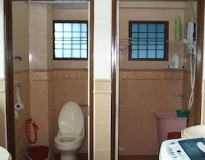 Un bagno con il water, una piccola finestra, zona doccia e lavandino.