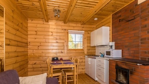 A cozy cabin interior with a wooden dining area, white cabinets, a brick fireplace, and a purple sofa. - Joutsen by Interhome (Jämsä)