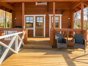 A wooden cabin with a porch, two wicker chairs, and a wooden deck. - Joutsen by Interhome (Jämsä)