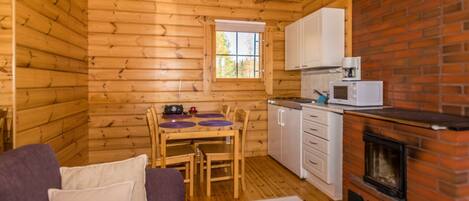 L’intérieur d’une cabane en rondins comprend un coin repas, une petite cuisine et une cheminée.