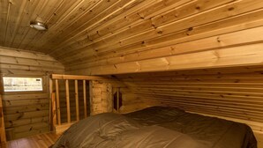 A wooden cabin room with a bed, a window, and a sloped ceiling. - Joutsen by Interhome (Jämsä)