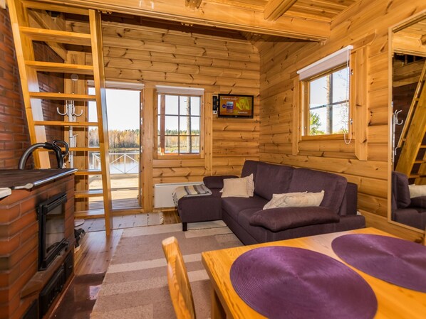 A cozy cabin interior with a fireplace, a sofa, and a television. - Joutsen by Interhome (Jämsä)