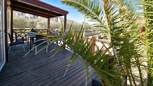 Een houten terras met tuinmeubilair, een overdekte zithoek en uitzicht op het omliggende landschap.