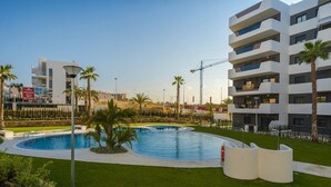 A modern building with multiple balconies, a swimming pool, and palm trees. - Apartamento Arenales (Arenales del Sol) (Arenales del Sol)