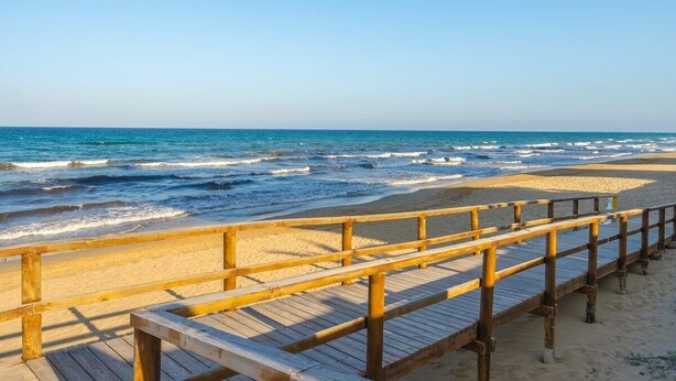A wooden boardwalk leading to a sandy beach with the ocean in the background. - Apartamento Arenales (Arenales del Sol) (Arenales del Sol)