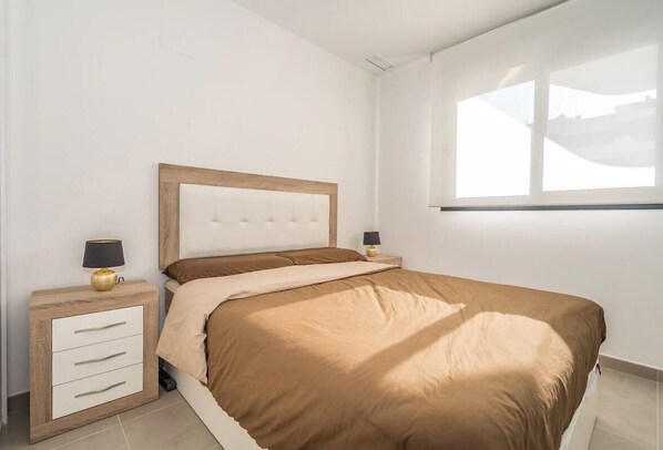 A bedroom with a bed, two bedside tables, and a window. - Apartamento Arenales (Arenales del Sol) (Arenales del Sol)