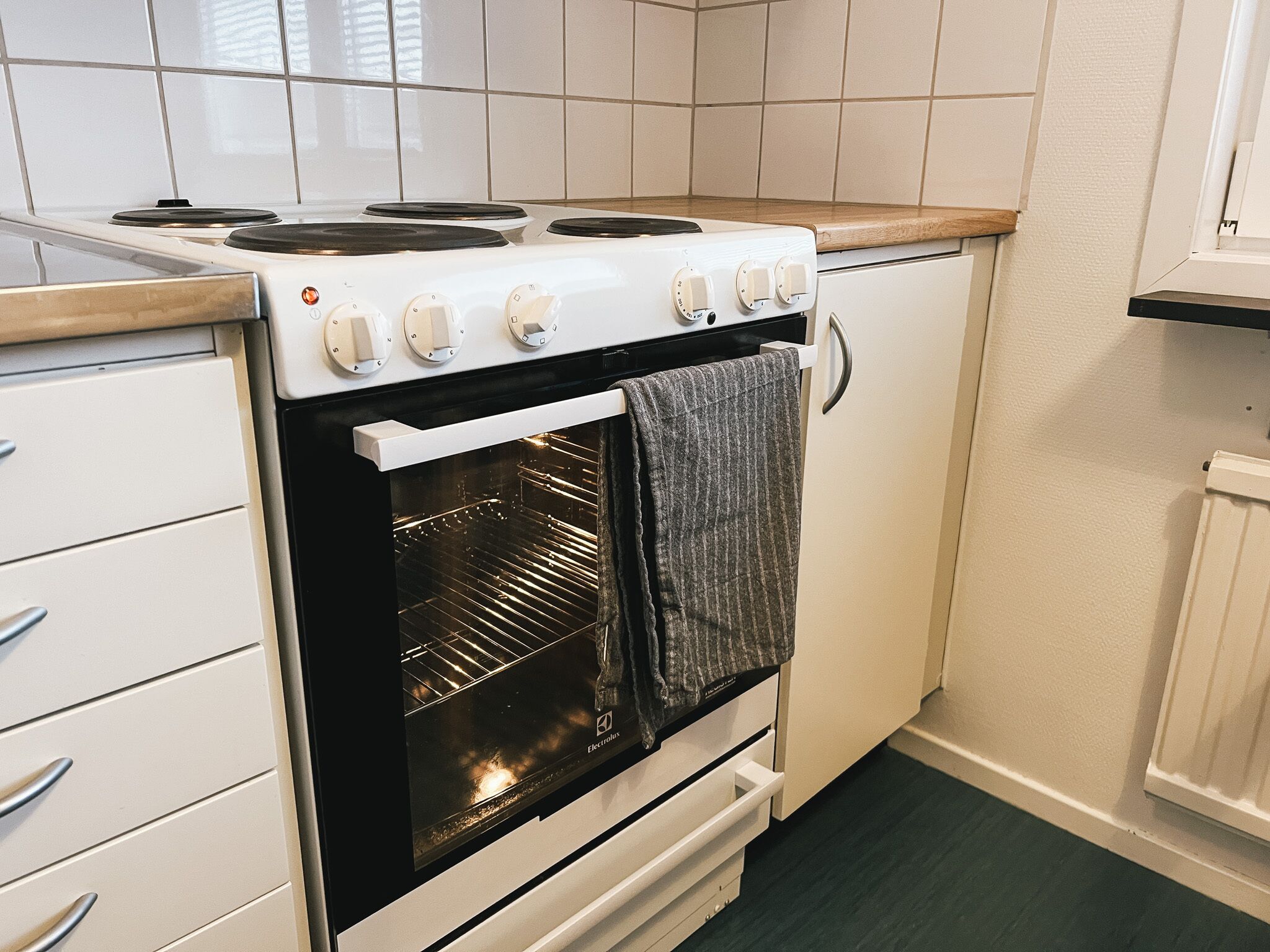 A kitchen with a white stove, oven, and cabinets.