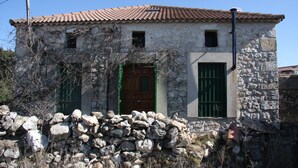 A stone building with a tiled roof, a wooden door, and green shutters. - Precious century-old house recently restored, original stone and wooden beams (Segovia)