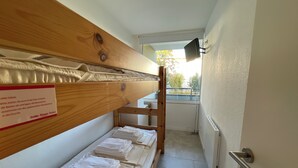 A bunk bed room with neatly folded towels and a sign on the headboard.