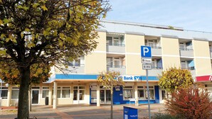 A multi-story building with a parking sign, a bank, and a restaurant.