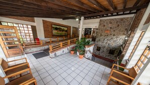 A spacious lobby with wooden chairs, a stone fireplace, and a tiled floor. - Hotel del Campo (Quetzaltenango)