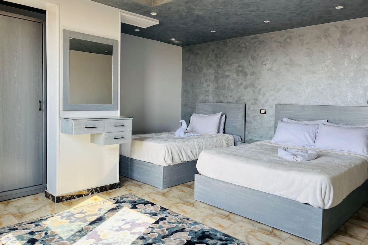A modern bedroom with two beds, a built-in wardrobe, and a large mirror.