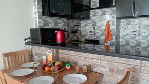A kitchen with a dining table set for two, a microwave, a red coffee maker, and a tiled backsplash. - Pyramids Terrace INN (Giza)