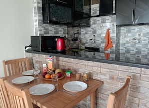 A kitchen with a dining table set for two, a microwave, a red coffee maker, and a tiled backsplash. - Pyramids Terrace INN (Giza)